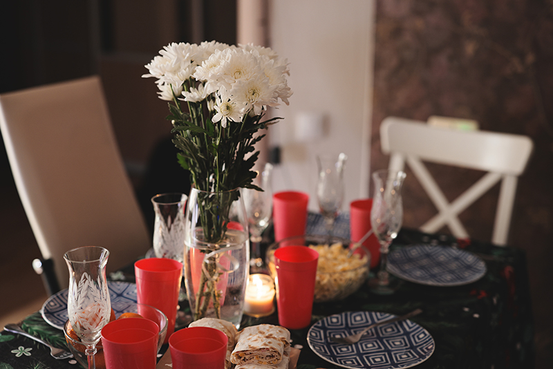 Vista de una mesa decorada con varios platos, vasos, copas de vino y flores blancas.
